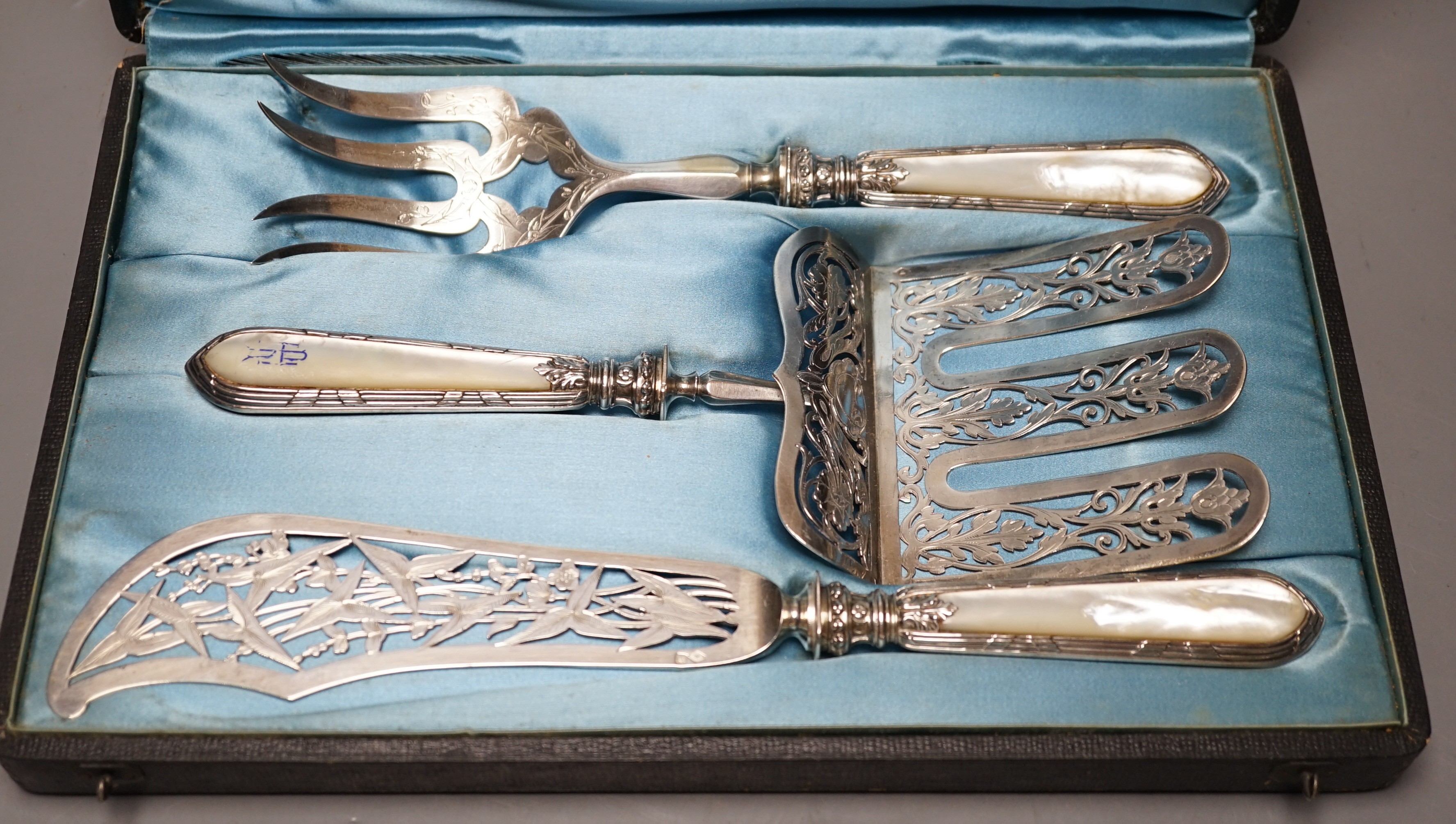 A cased ornate French white metal and mother of pearl mounted serving set, comprising a pair of fish servers and a cake server, maker JM.